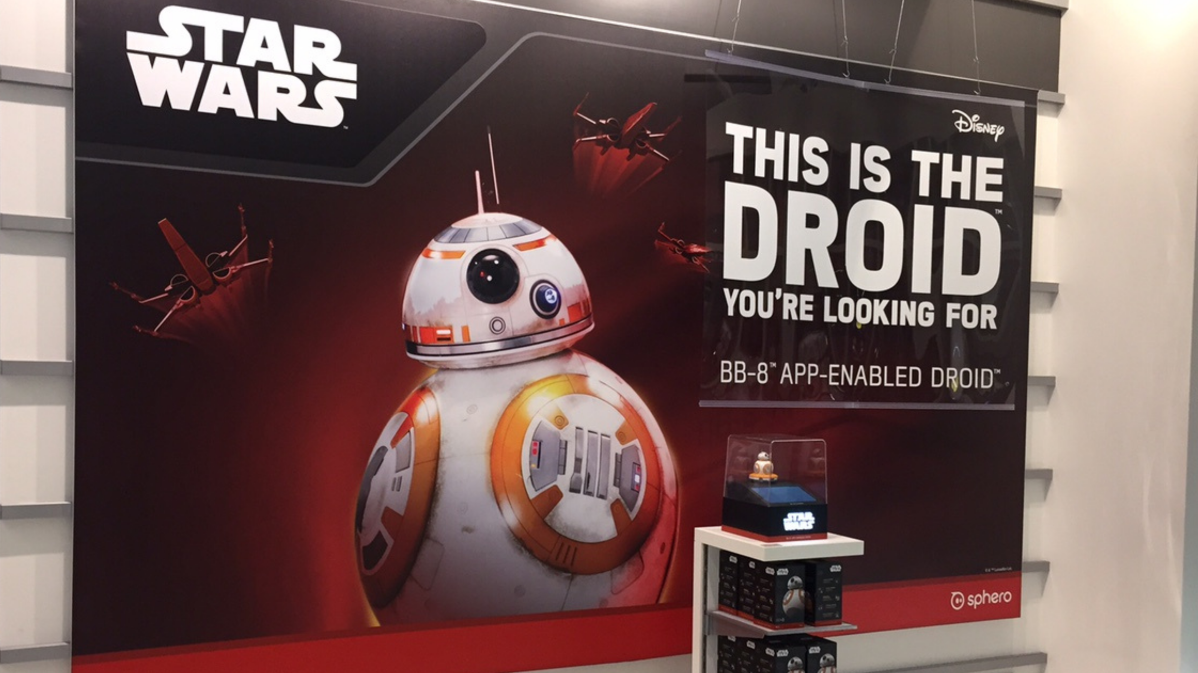 In-store wall graphic of BB-8 with Star Wars logo and a hanging banner reading 'This is the droid you're looking for'