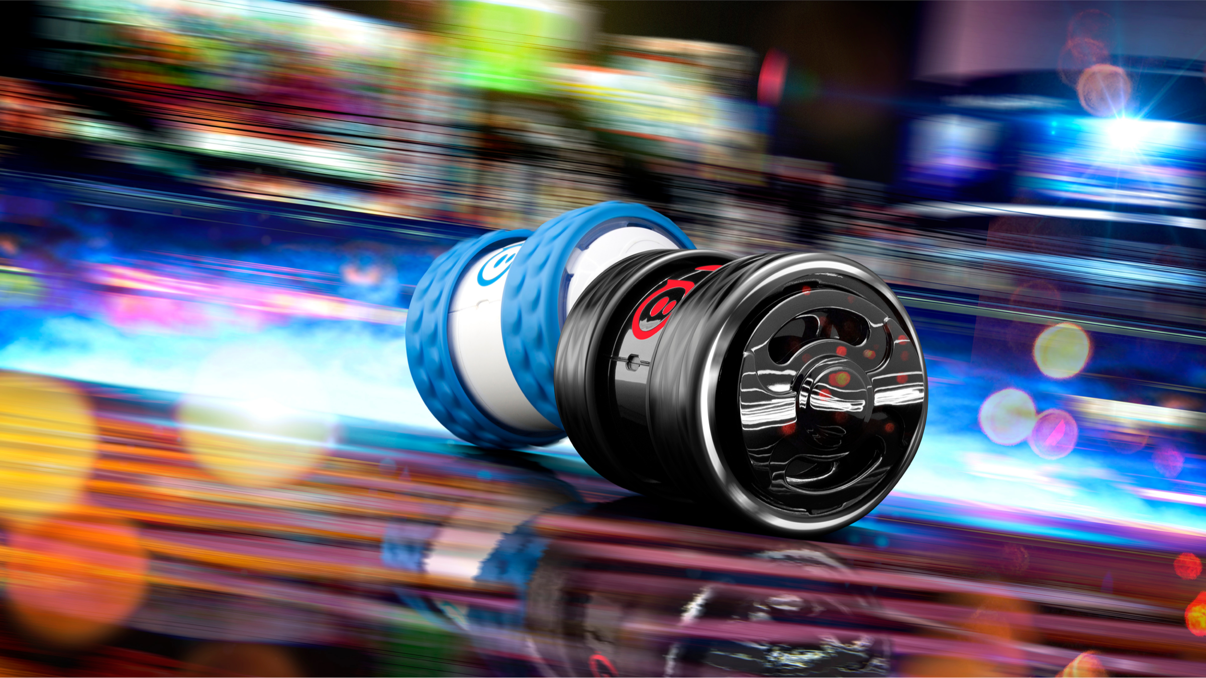 Two Sphero Ollie tube robots, one white with blue tires and one black with red trim, speeding through neon light streaks